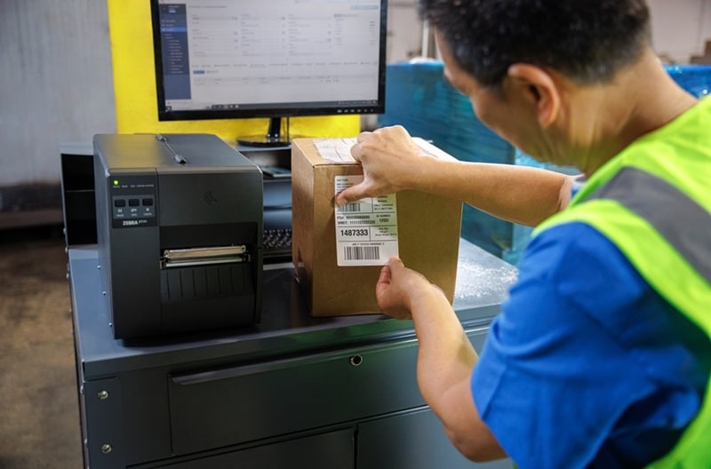 Warehouse worker applying thermal shipping labels to a carton